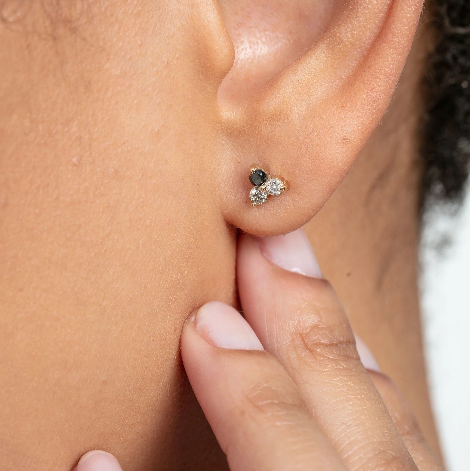 Trilogy diamond studs with white, grey, and black diamonds on model.